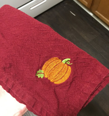 picture of a red burgundy napkin with a pumpkin design on it, bought from a local thrift store to avoid single use napkins