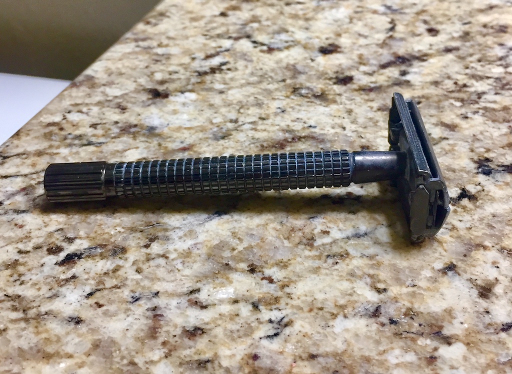 A picture of a metal safety razor on the bathroom counter