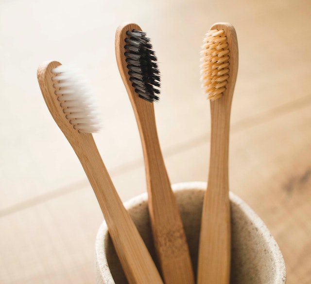 A picture of three bamboo toothbrushes in a cup