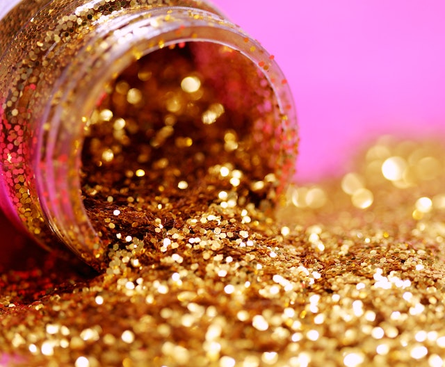 A picture of a jar of gold glitter, with the glitter spilling out 