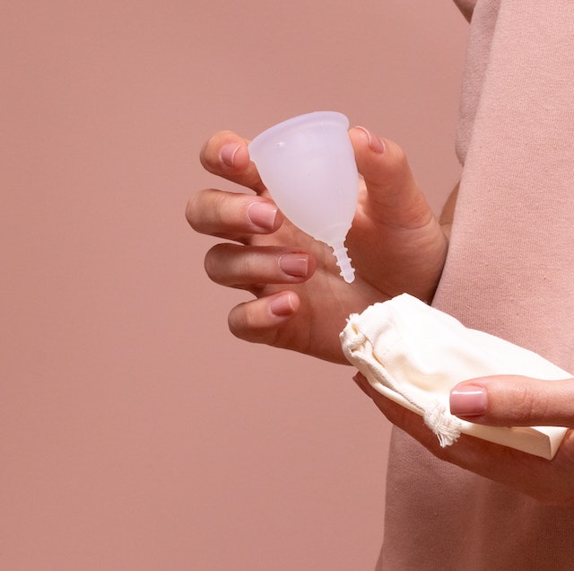 A picture of a woman holding a pink menstrual cup