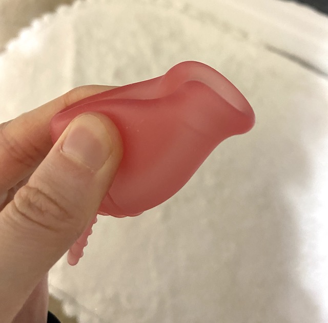 A picture of a pink menstrual cup in the push down fold