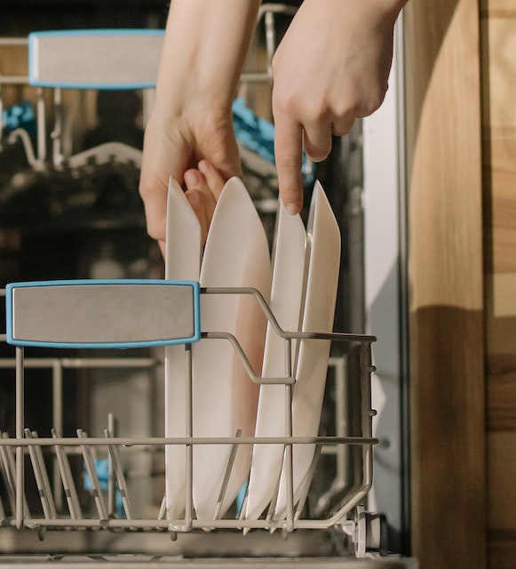 A picture of hands putting a dish in the dishwasher