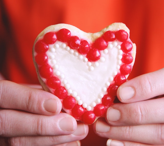 A picture of two hands holding a heart cookie