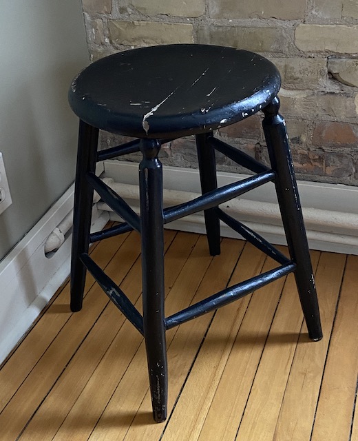 A picture of a black stool with chips and cracks
