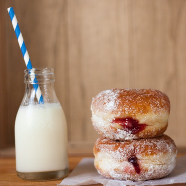 A picture of two paczki donuts and a glass of milk
