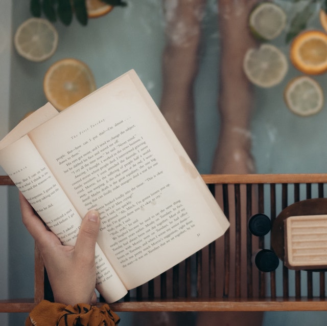 A picture of someone reading a book about sustainability in the bathtub