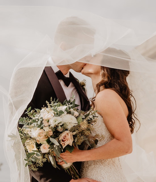 A picure of a man and woman kissing at their wedding