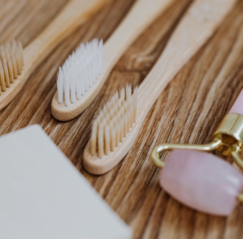 A picture of two bamboo toothbrushes lying on a wooden surface