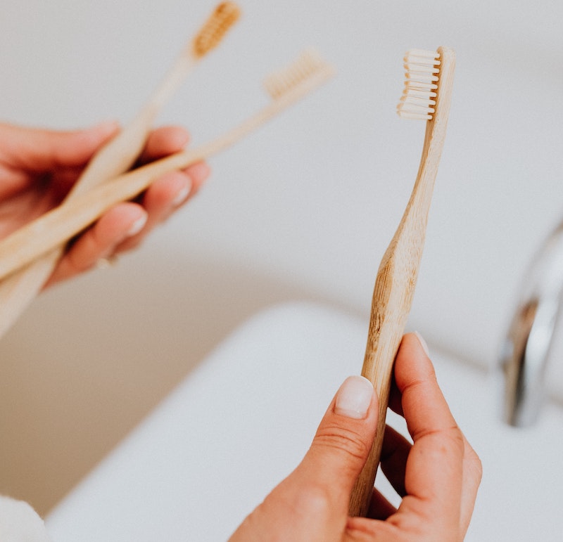 A picture of a hand holding a bamboo toothbrush