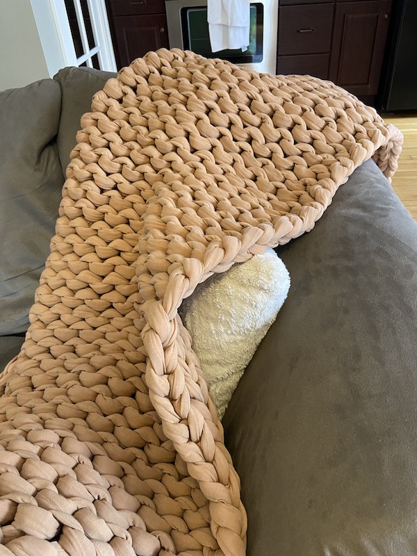 A picture of a Bearaby Tree Napper weighted blanket on the couch
