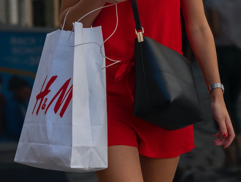 A picture of a woman in a red dress carrying an H&M fashion bag