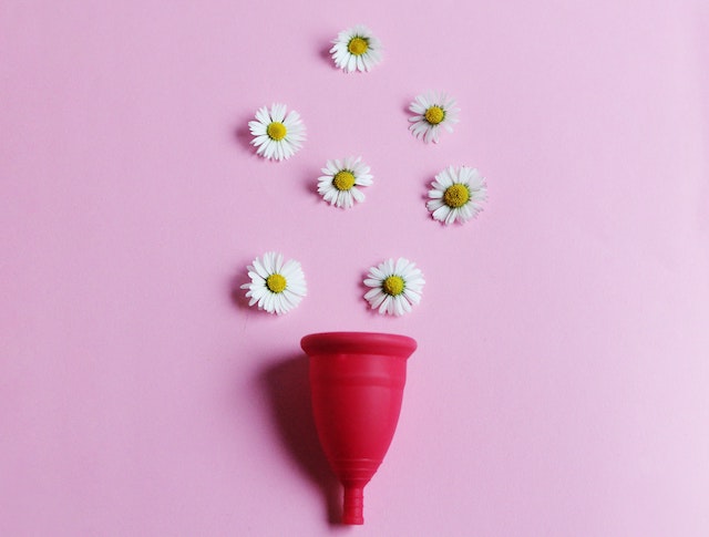 A picture of a menstrual cup with flowers spilling out of it