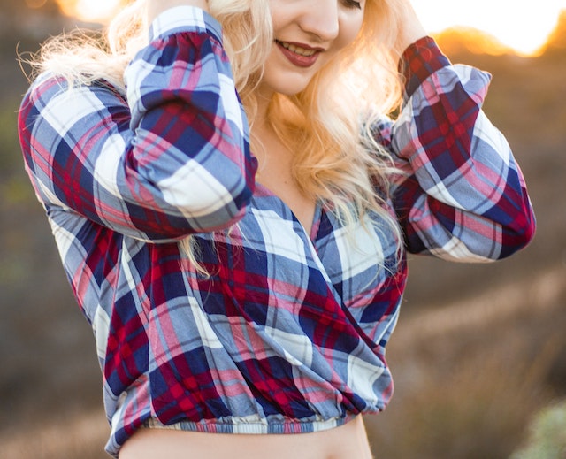 A picture of a blonde girl wearing a red, white, and blue plaid shirt