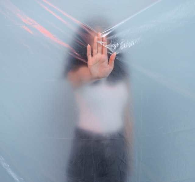 A woman standing behind a plastic screen 