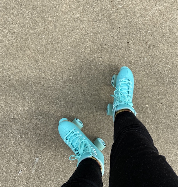 Pair of teal roller skates on an outdoor rink